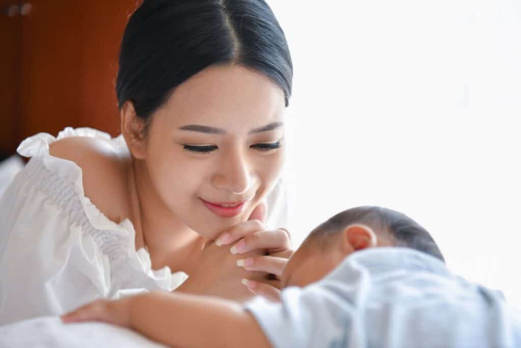 Woman smiling over sleeping baby