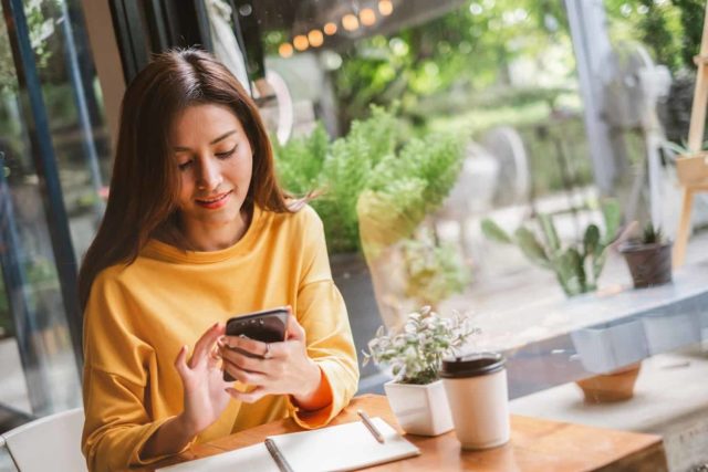 woman smiling while scrolling on a smartphone